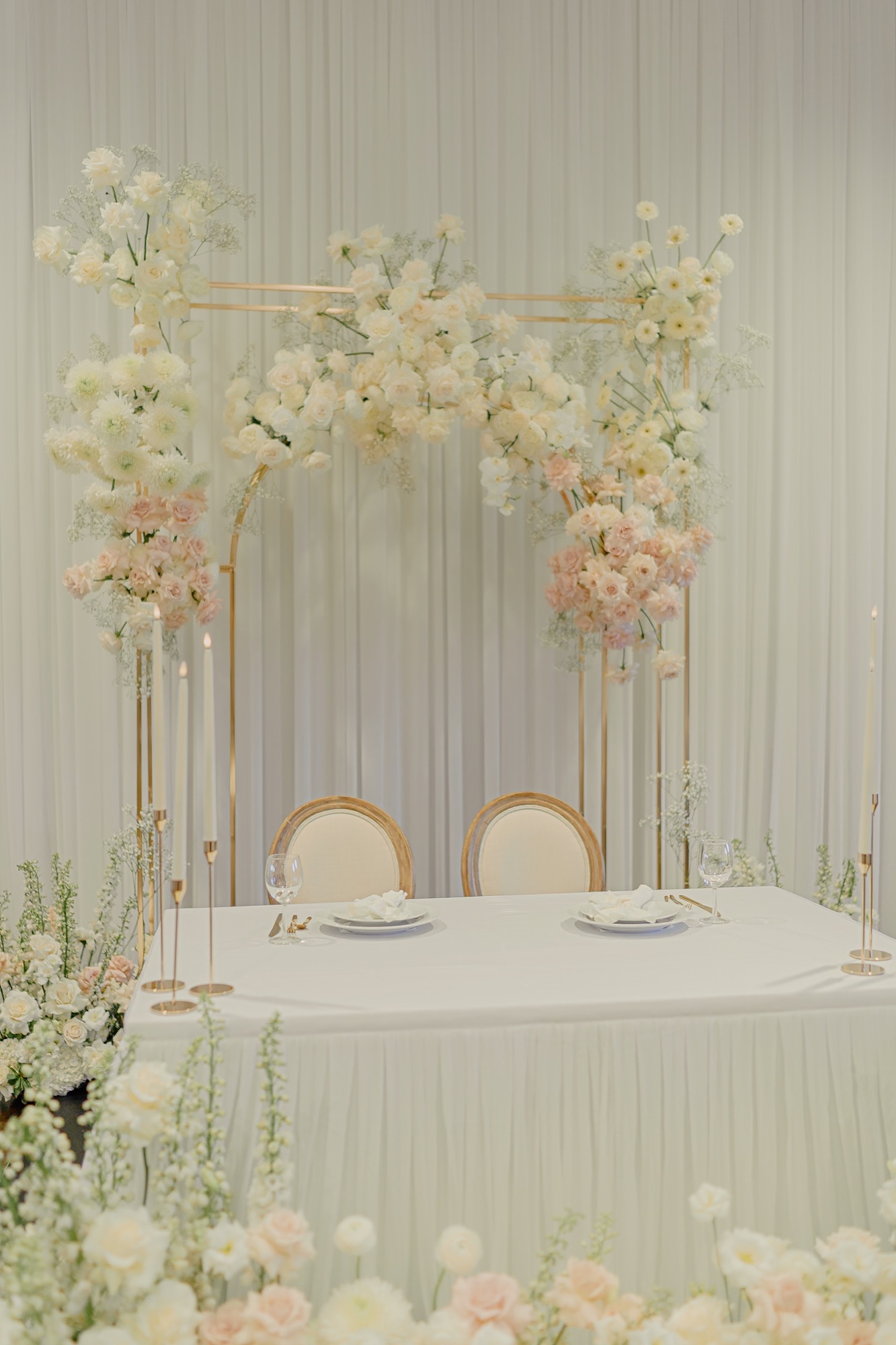 A gold arch sweetheart table dressed in cream and blush florals