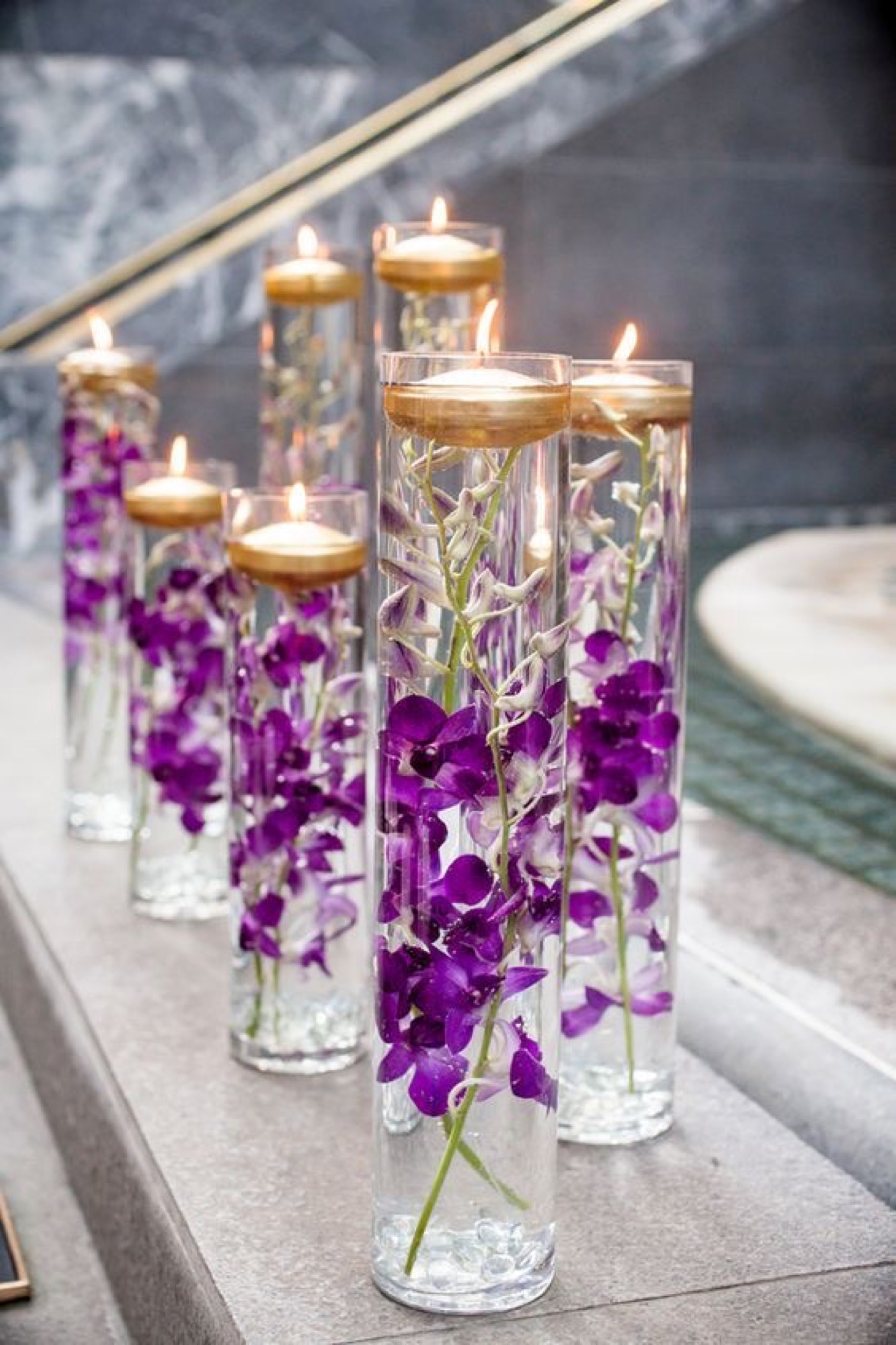 Submerged purple orchids in cylinder vases with floating candles